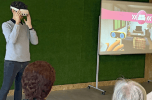 un joven muestra a personas mayores el funcionamiento de un dispositivo de realidad virtual