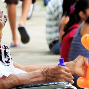 Una señora mayor, en silla de ruedas que observa junto a su familia una actividad infantil en un barrio pobre de Costa Rica (Foto presentada a la edición 11 del  Concurso de Fotografía Digital del INICO - Fundación Grupo Norte)