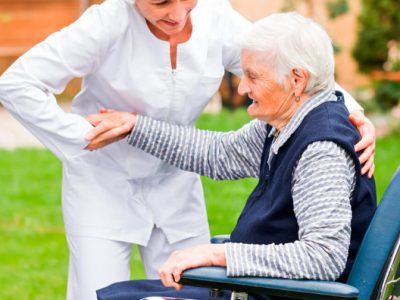 Una cuidadora ayuda a una mujer mayor a levantarse