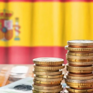 monedas apiladas y la bandera de España de fondo